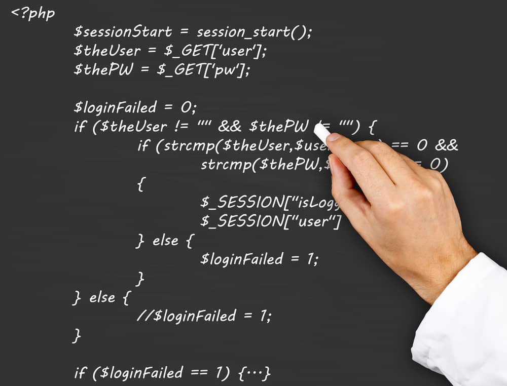Mano escribiendo código fuente PHP en una pizarra, mostrando un ejemplo de sintaxis y estructura.