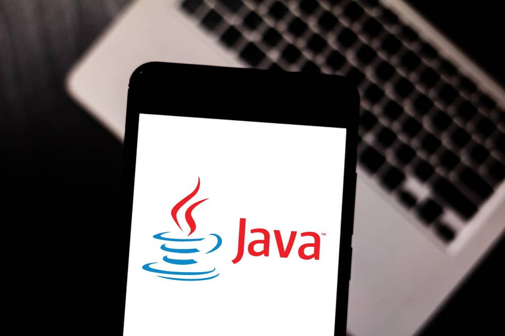 El logo de Java en un teléfono móvil sobre un teclado de portátil, ilustrando el uso de Java en aplicaciones.